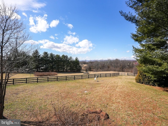 view of yard with fence and a rural view