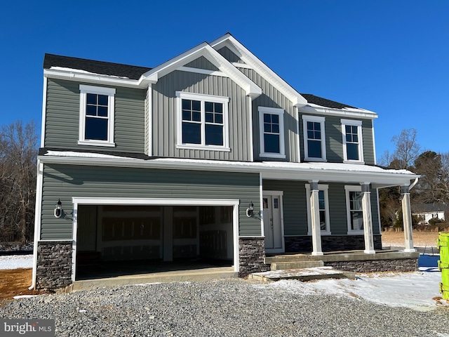 view of front of house featuring a porch, a garage, stone siding, driveway, and board and batten siding