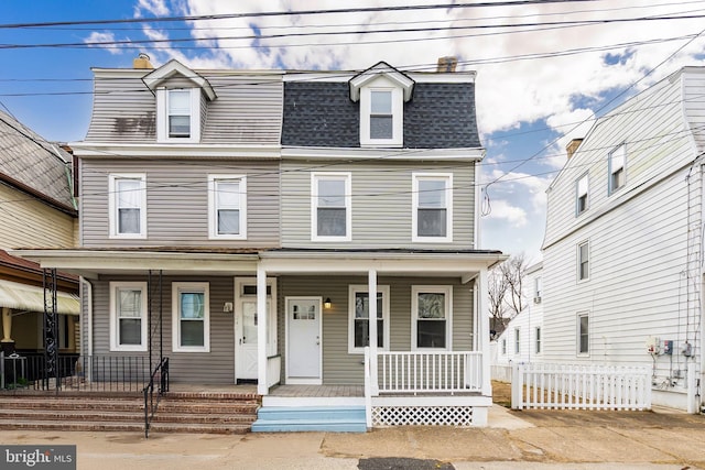 view of front facade featuring a porch, a shingled roof, and mansard roof