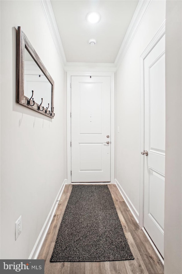 entryway with light wood-style flooring, baseboards, and crown molding