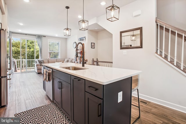 kitchen featuring recessed lighting, wood finished floors, a sink, open floor plan, and hanging light fixtures