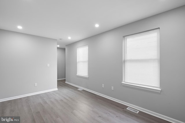 unfurnished room featuring light wood finished floors, recessed lighting, visible vents, and baseboards