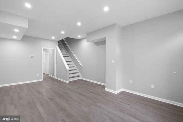 basement featuring baseboards, stairway, wood finished floors, and recessed lighting