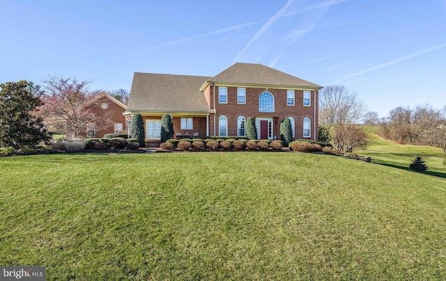 georgian-style home featuring brick siding and a front yard