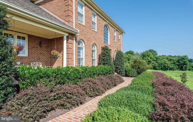 view of home's exterior with brick siding and a shingled roof