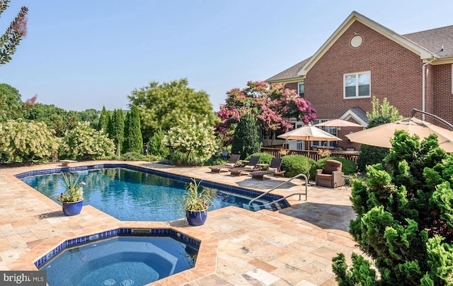 outdoor pool featuring a patio area and an in ground hot tub