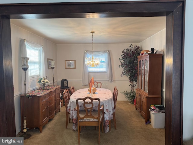 dining space featuring a healthy amount of sunlight, an inviting chandelier, and light carpet