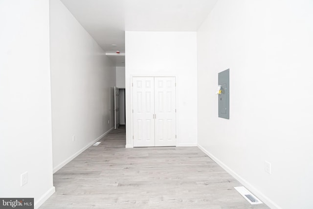 unfurnished bedroom with light wood finished floors, electric panel, visible vents, baseboards, and a closet