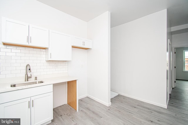 kitchen featuring white cabinets, light countertops, and a sink