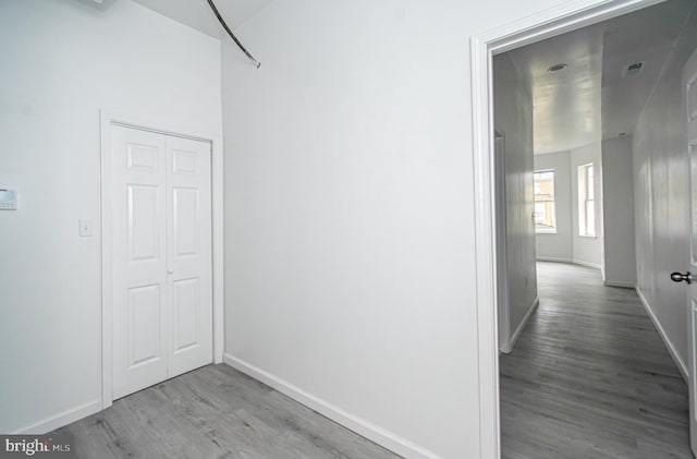 corridor with light wood finished floors, baseboards, and visible vents