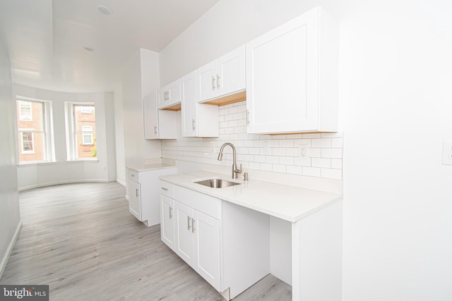 kitchen featuring light countertops, a sink, white cabinetry, and decorative backsplash