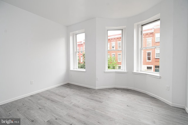 unfurnished room with light wood-type flooring and baseboards