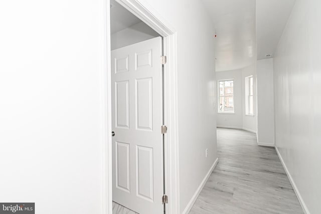 hallway featuring light wood-style flooring and baseboards