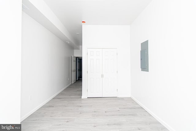 spare room featuring light wood-style floors, electric panel, and baseboards