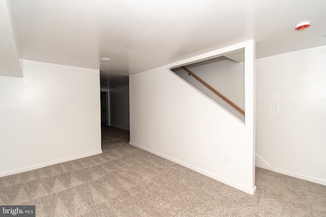 unfurnished room with stairs, baseboards, and light colored carpet