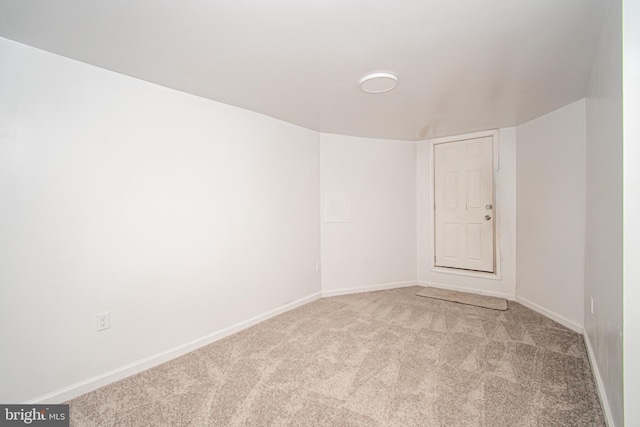 spare room with baseboards and light colored carpet