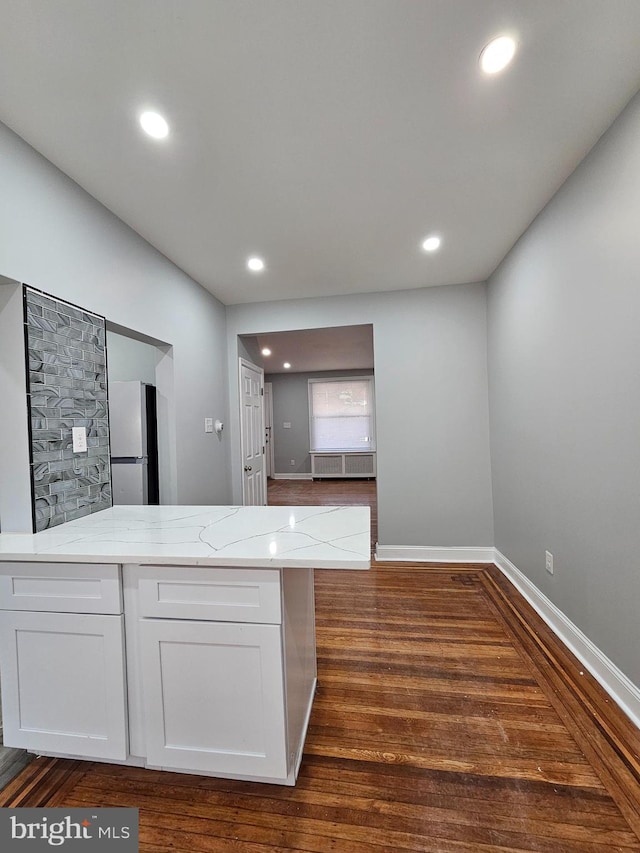 kitchen featuring dark wood-style floors, light stone counters, recessed lighting, freestanding refrigerator, and white cabinetry