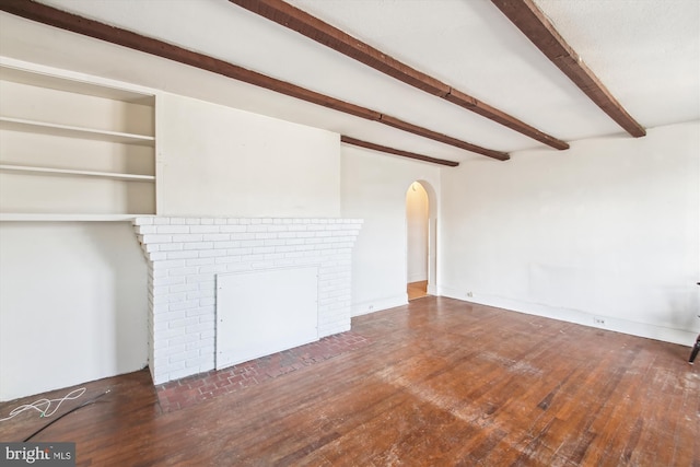 unfurnished living room featuring a fireplace, arched walkways, dark wood-type flooring, and beamed ceiling