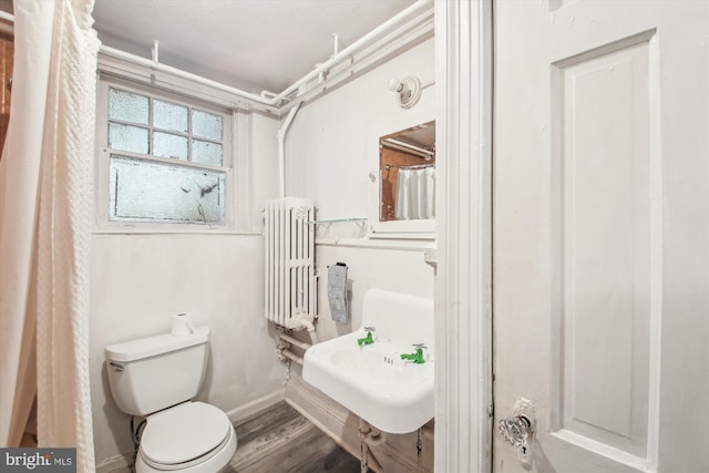 full bathroom featuring baseboards, toilet, radiator heating unit, wood finished floors, and a sink