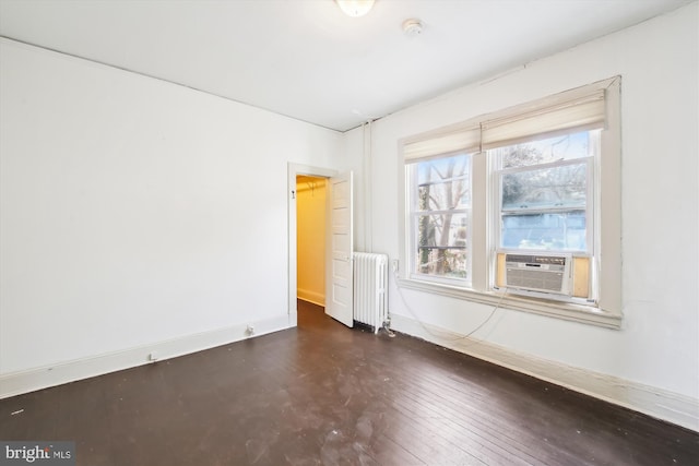 spare room featuring radiator heating unit, cooling unit, dark wood finished floors, and baseboards