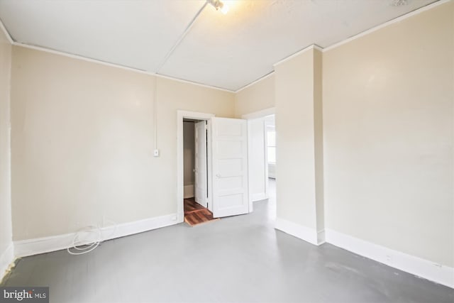 unfurnished room featuring baseboards, concrete flooring, and ornamental molding