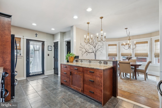 kitchen featuring light stone counters, recessed lighting, hanging light fixtures, a chandelier, and baseboards