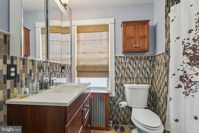 full bath with wainscoting, tile walls, toilet, and vanity