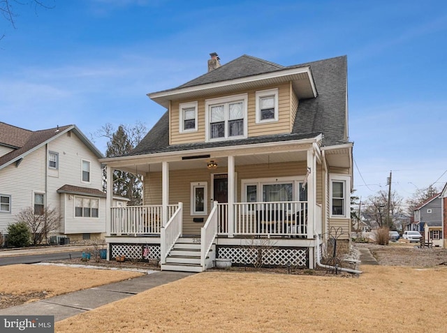 view of front facade featuring covered porch, roof with shingles, a chimney, and central AC unit