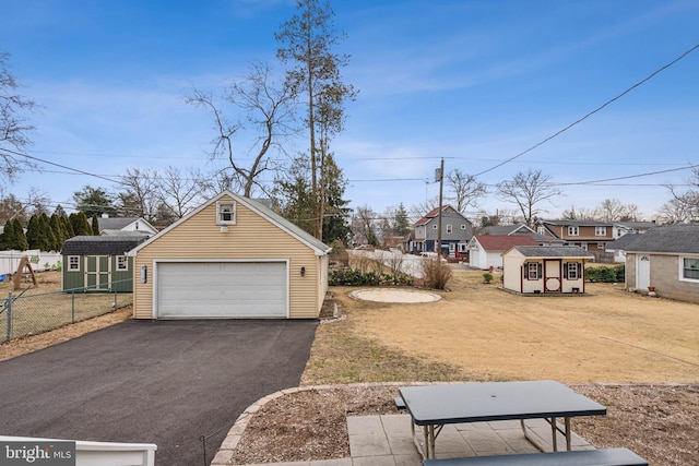 view of yard with a storage unit, fence, a garage, a residential view, and an outdoor structure