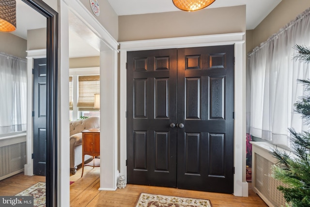 foyer entrance with light wood-style floors and radiator heating unit