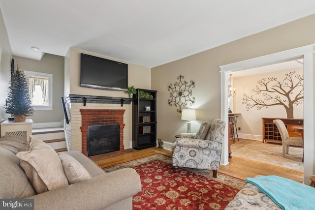 living room with a brick fireplace, baseboards, and wood finished floors