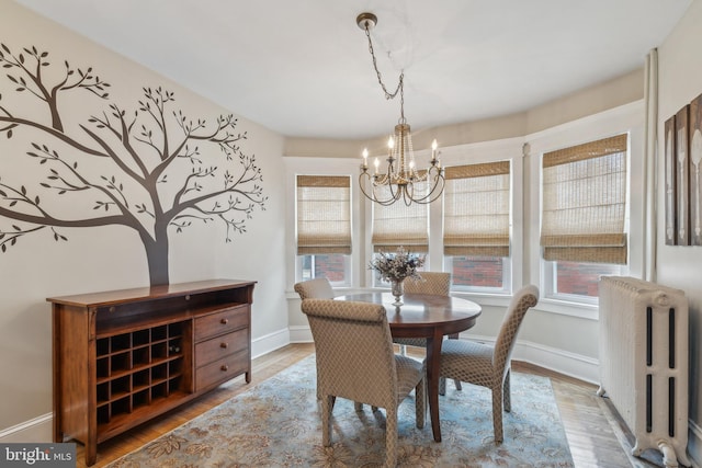 dining area featuring a chandelier, baseboards, wood finished floors, and radiator