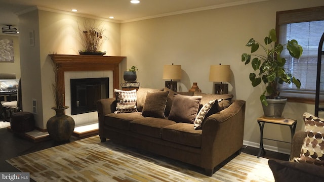 living area with baseboards, a tiled fireplace, light wood-style flooring, crown molding, and recessed lighting