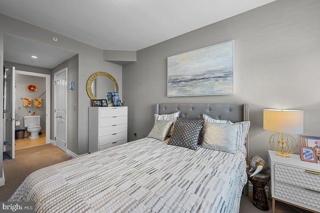 carpeted bedroom with ensuite bath and baseboards