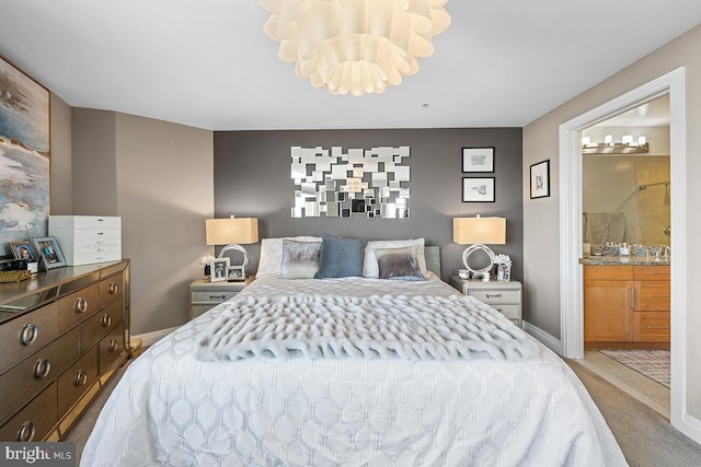 bedroom with baseboards, connected bathroom, and light colored carpet