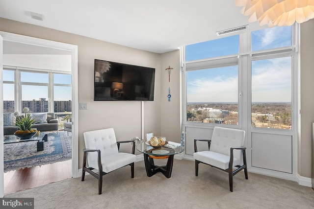 sitting room featuring light colored carpet, visible vents, plenty of natural light, and baseboards