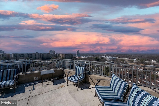 patio terrace at dusk with a view of city and a balcony