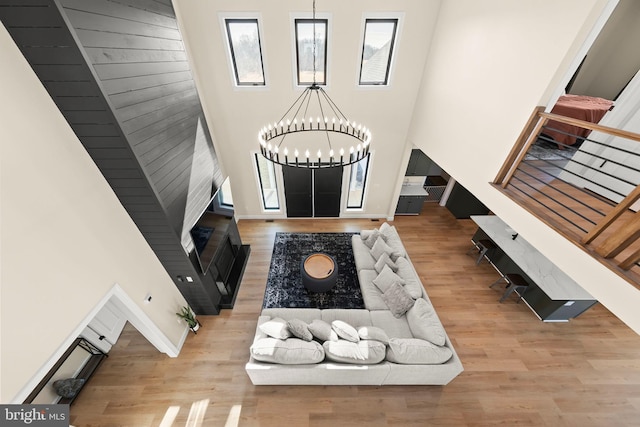 entrance foyer featuring stairs, light wood-type flooring, a towering ceiling, and an inviting chandelier