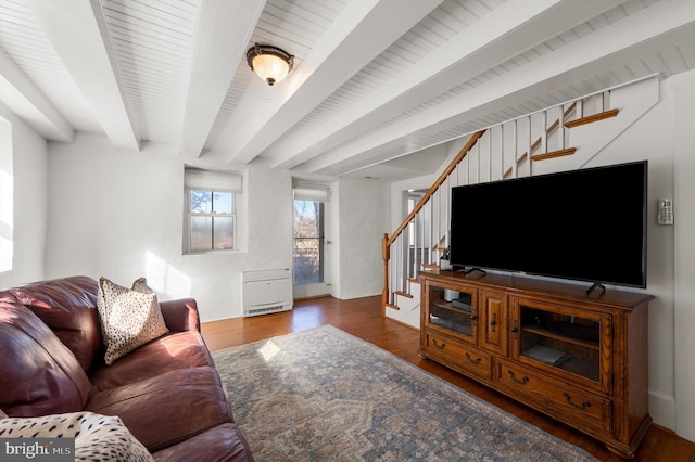 living room featuring dark wood-type flooring, beam ceiling, and stairs