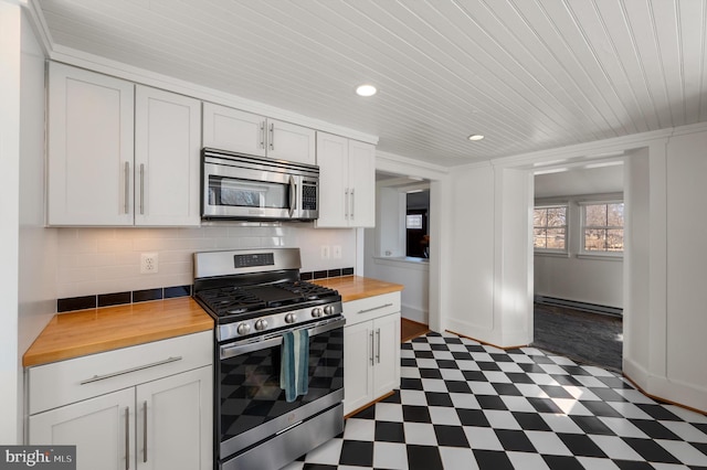 kitchen with butcher block countertops, dark floors, stainless steel appliances, white cabinetry, and a baseboard heating unit