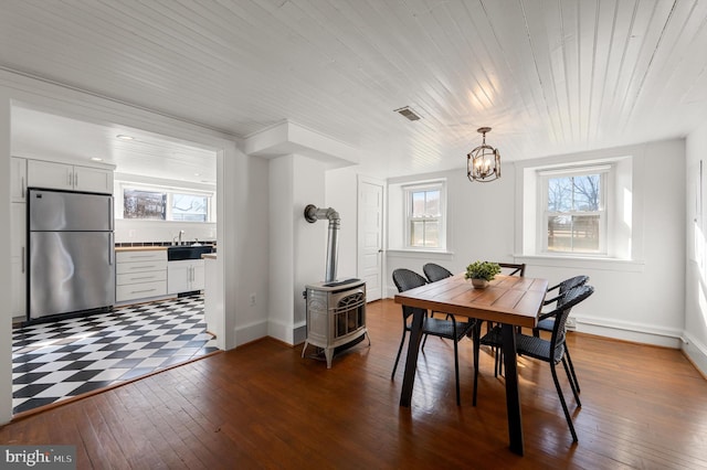 dining room with a healthy amount of sunlight, a wood stove, and dark wood-style flooring