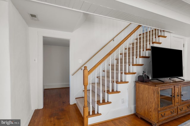 staircase with baseboards, visible vents, and wood finished floors