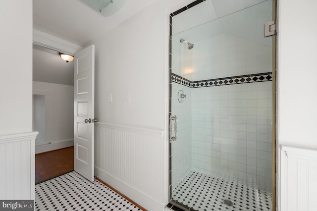 bathroom with a wainscoted wall and a shower stall