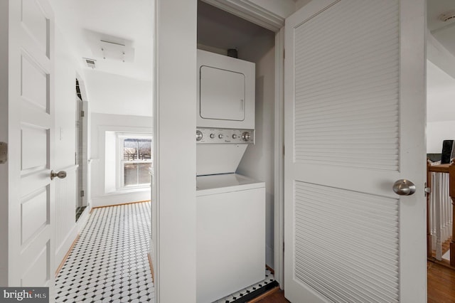 washroom featuring visible vents, stacked washer and dryer, and laundry area