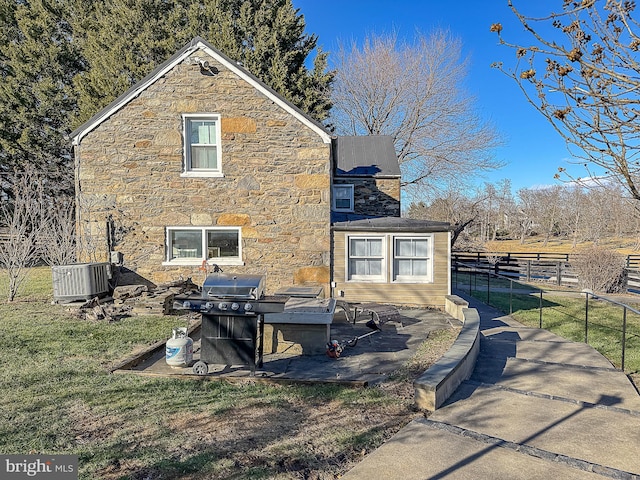 view of home's exterior featuring a patio area, fence, metal roof, cooling unit, and stone siding