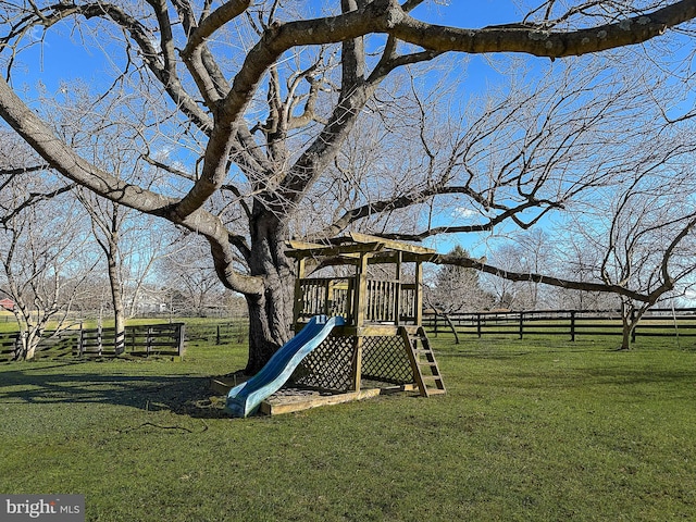 view of play area with fence, a lawn, and a rural view