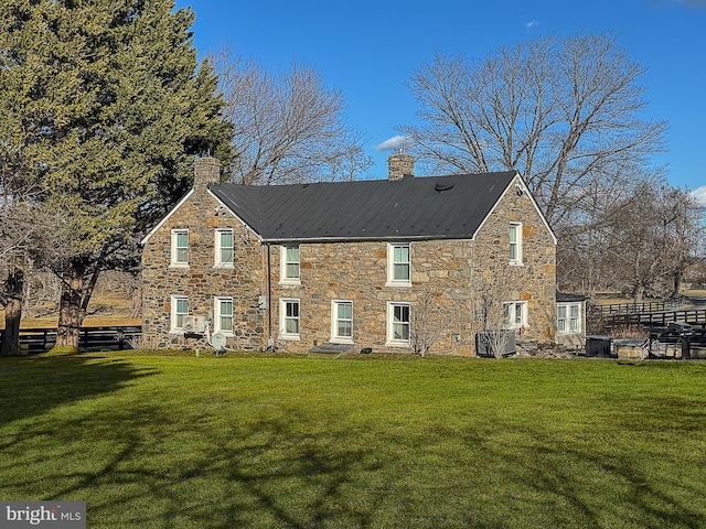 view of front of property with a front yard, stone siding, and a chimney