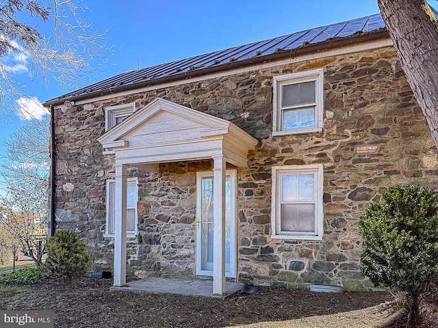 exterior space featuring stone siding, metal roof, and a standing seam roof