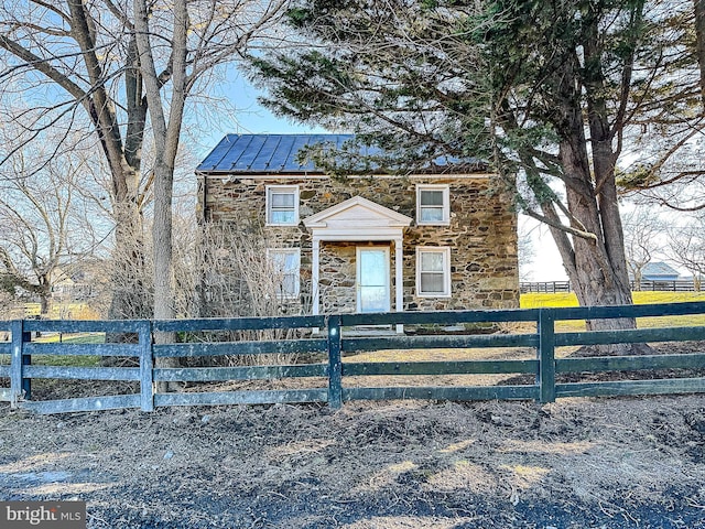 view of front of home featuring stone siding, a fenced front yard, metal roof, and a standing seam roof