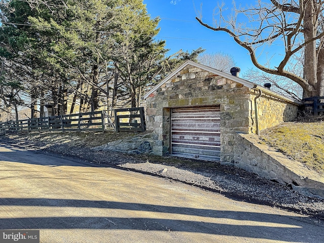 detached garage featuring driveway and fence